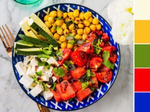 Colorful turmeric chickpea watermelon salad with feta cheese, tomatoes, zucchini, mint and balsamic vinegar on marble table Colorful turmeric chickpea watermelon salad with feta cheese, tomatoes, zucchini, mint and balsamic vinegar on marble table