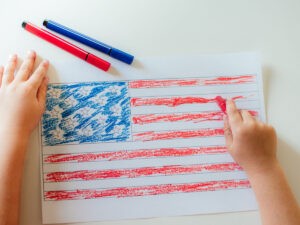 The child's hands paint the American flag on a white table 