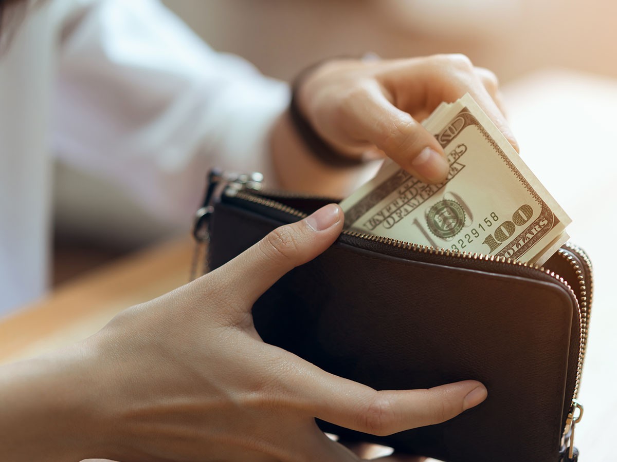 Image of a person putting money in their wallet